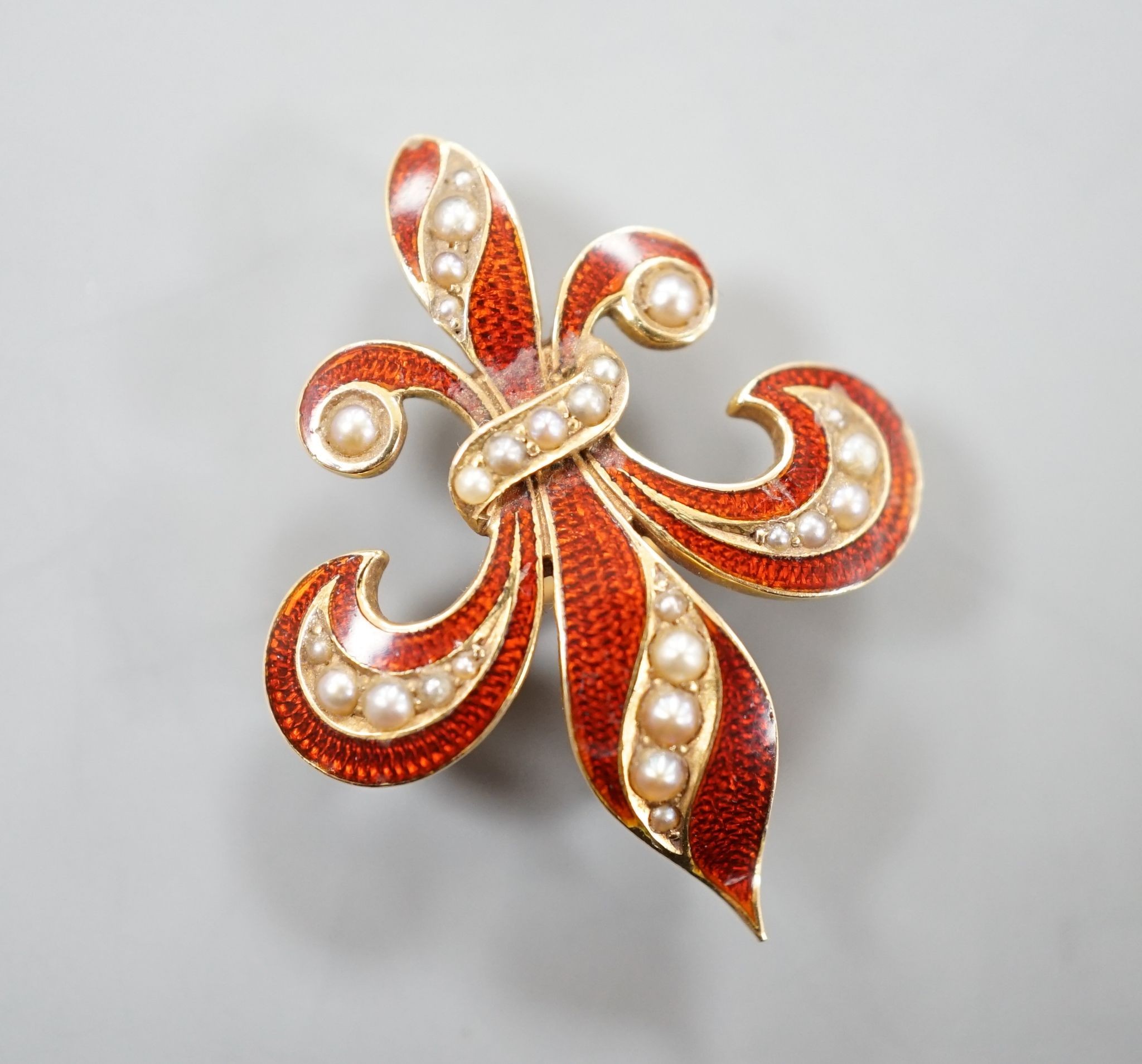 A continental 14k yellow metal, red enamel and graduated seed pearl set fleur du lis brooch, 29mm, gross weight 5.3 grams.